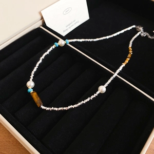 Detail of beaded necklace with tiger eye stone and pearls on black velvet jewelry box