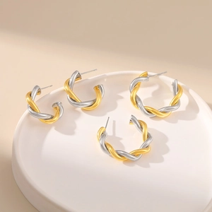 Detailed comparison of two sizes of gold and silver twisted hoop earrings on white ceramic
