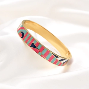 Detail of gold-plated stainless steel bangle with colorful geometric enamel on white silk