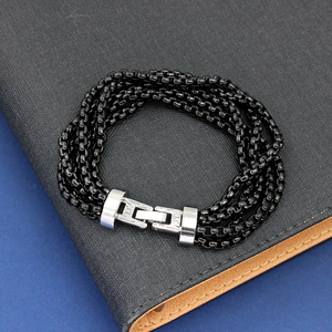 Macro view of multi-layer black chain bracelet with silver clasp on a notebook