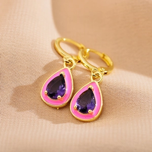 Close-up of golden teardrop earrings with purple gemstone and pink enamel inlay detail