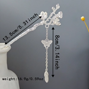 Detail of silver branch hairpin with butterfly charm and leaf tassel in a vase