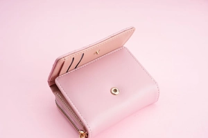 Detail of pink three-fold wallet showing card slots and golden zipper coin pocket
