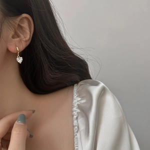 Close-up of elegant gold heart-shaped zircon drop earrings worn by a model
