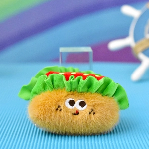Close-up of a cute furry croissant-shaped plush pendant with large embroidered eyes.