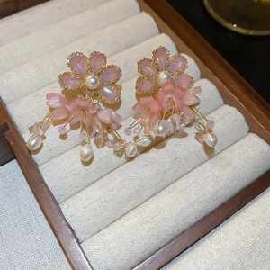 Detail view of pink flower earrings with freshwater pearl tassels in a beige jewelry box