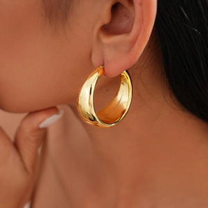 Detailed close-up of a high-polish gold round hoop earring worn by a model