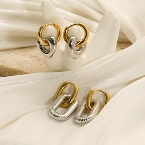 Two-tone heart and geometric earrings in gold and silver finish with white hand model display