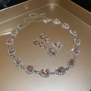 Macro shot of pink pear-cut gemstone jewelry set with necklace and earrings on gold tray