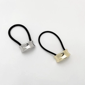 Macro detail of elastic hair ties featuring polished gold and silver metal cylinder sliders