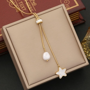 Detail view of gold lariat necklace with baroque pearl and star pendant on display