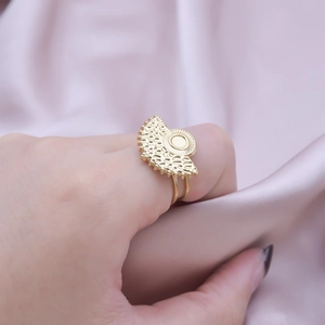 Close-up of bohemian gold fan-shaped ring with cutout details on satin background