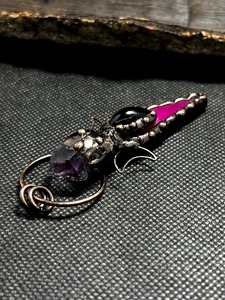 Macro shot of bronze pendant featuring amethyst and agate stones on dark textured surface