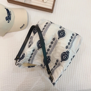 Detail view of ethnic embroidery patterns on white canvas tote bag with black leather strap