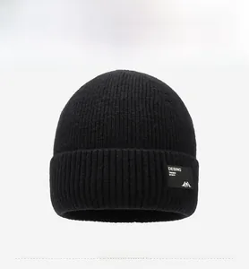 Detailansicht der schwarzen Strickmütze mit Logo-Patch und warmer Wintertextur für Herren