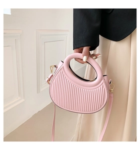Close-up of pink saddle bag featuring vertical striped texture and gold hardware detail