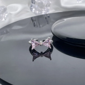 Macro shot of silver bow ring with pink zircon crystals on reflective surface