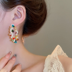 Close-up of pearl and colorful faceted bead wrap earrings on model with gold hardware