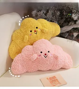 Close-up of cloud-shaped plush pillows in yellow and pink with cute embroidered smiles