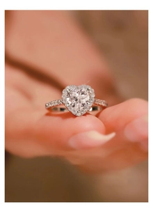 Close-up of heart-shaped moissanite ring in rose gold with pave setting on model hand