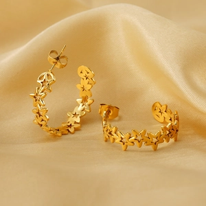 Detailed view of hollow star-shaped gold earrings on a premium silk fabric background