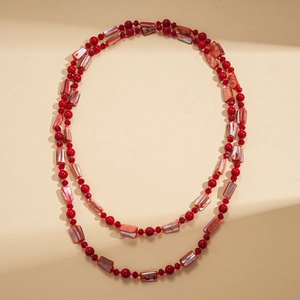 Detail view of double-layered long necklace with red beads and natural shell pendants