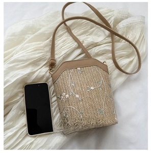 Comparaison de taille du sac seau en paille avec broderie florale et un smartphone