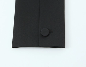 Détail de la manche en tissu noir tissé avec un bouton recouvert assorti en gros plan