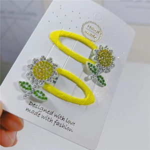 Detail of two handmade sunflower hair clips with yellow rhinestones on a display card