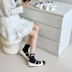 Detail of black cotton JK mid-calf socks with white bows and wavy lace trim on model