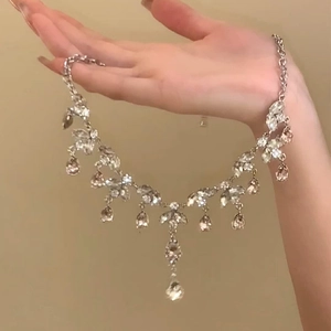 Detail of silver drop pendant necklace with clear and champagne crystals held in hand