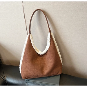 Detail view of brown suede shoulder bag with white faux fur trim and leather strap