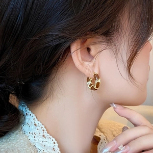 Boucles d'oreilles créoles dorées vintage avec résine brune portées sur dentelle blanche