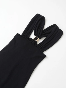 Detail of elegant black knitted dress featuring a gold square buckle and pleated halter neck design