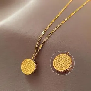 Macro detail of gold stainless steel necklace featuring Fu and Xi character round pendants