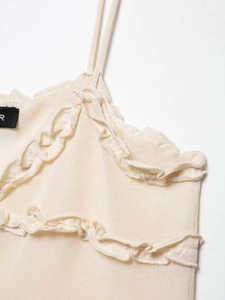 Detailed close-up of cream knit camisole featuring delicate ruffle edge trim details