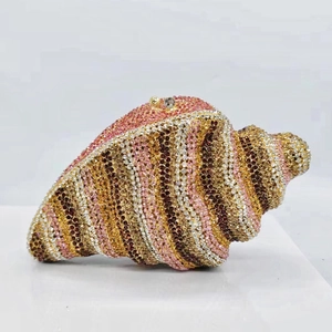 Macro detail of luxury conch shell clutch bag with gold and pink crystal embellishments