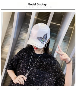 Detailed view of white satin baseball cap with sparkling rhinestone butterfly embellishment