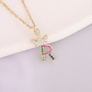 Macro shot of 18K gold plated crown and R letter pendant with colorful zircon stones