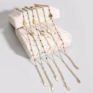 Detail of stainless steel bracelets with colorful beads and golden sun charms on stone