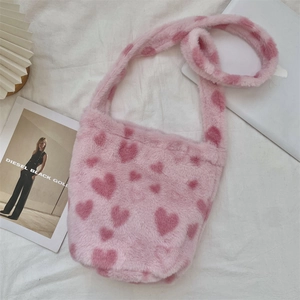 Detailed shot of pink faux fur shoulder bag with heart pattern on white fabric