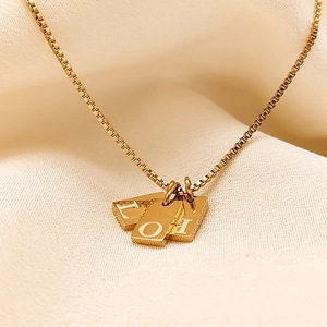 Macro shot of gold square pendants with L, O, H letters on a delicate box chain