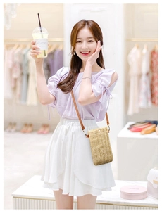 Straw woven phone bag in khaki with leather strap shown in a summer fashion style