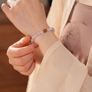 Detail of beaded purple kunzite bracelet with gold spacers worn on a female wrist