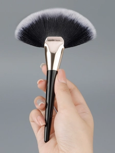 Close-up of large fan makeup brush with soft dual-tone bristles and sleek black handle
