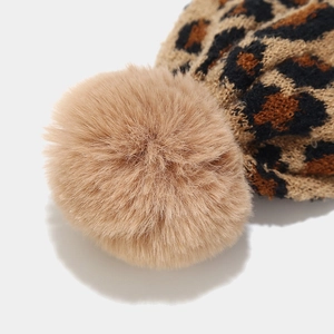 Detailed close-up of leopard jacquard knit beanie with a fluffy faux fur pom-pom topper
