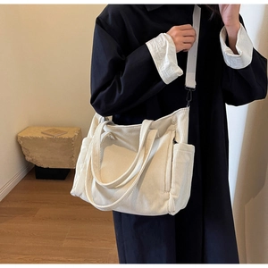 Detail of cream corduroy tote bag featuring ribbed texture and adjustable strap