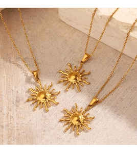 Trois colliers avec pendentif soleil plaqué or 18K sur une surface en pierre