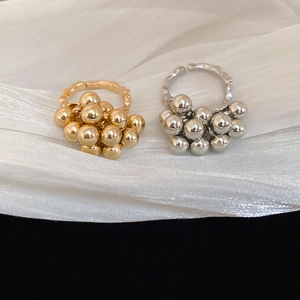 Macro shot of gold and silver cluster rings with metallic spheres on wavy bands