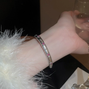 Detail eines silbernen Armreifs mit rotem Edelsteinbesatz und funkelnden Sternenmotiven